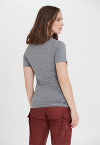 Grå kortärmad skjorta med en figurnära design, med raglanärmar. Bärs tillsammans med röda cargo-byxor som har dragkedjefickor.