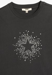 Czarnoszary bawełniany t-shirt z srebrnym wzorem gwiazdy ozdobionym rozproszonymi błyszczącymi kropkami, okrągłym dekoltem i krótkimi rękawami.