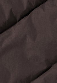 Donkerbruin stof met een gladde textuur en subtiele glans, voorzien van diagonale stiksels en een lichtgewicht, gewatteerd ontwerp.