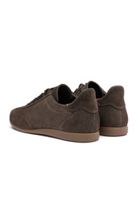 Sneakers in suede marrone con profilo basso, punta arrotondata, suola piatta in gomma e dettagli di cucitura a contrasto. Design adatto per abbigliamento casual.