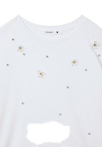 T-shirt bianca a maniche corte, con dettagli floreali applicati e decorazioni scintillanti. L'etichetta riporta "TERRANOVA" taglia S.
