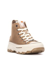 Zapatilla alta beige con cordones blancos, parte superior de ante texturizado, suela de goma y plataforma gruesa prominente. Parche de logo en la lengua.