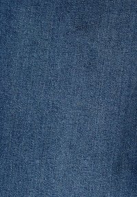 Gros plan d’un tissu en denim bleu montrant un motif de sergé diagonal et une surface texturée.