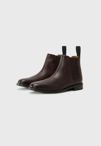 Bottines en cuir marron avec une finition lisse, panneaux latéraux élastiques et accents cousus. Équipées de languettes pour un enfilage facile.