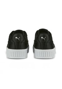 Zapatillas de cuero negro con un acabado texturizado, que presentan una suela de goma blanca y un pequeño logo de Puma en el talón. Forma redondeada.