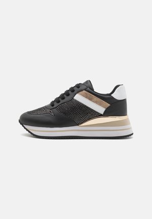 Sneaker nera con accenti in rete, strisce dorate e bianche, colletto imbottito, suola spessa e superfici testurizzate, con un design della punta arrotondata.