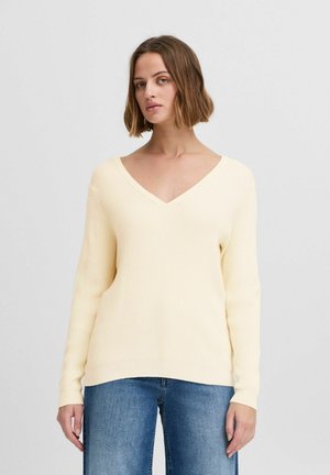 Pull en tricot côtelé jaune avec un col en V et des manches longues. L'ourlet est légèrement arrondi et le tissu a une texture douce.