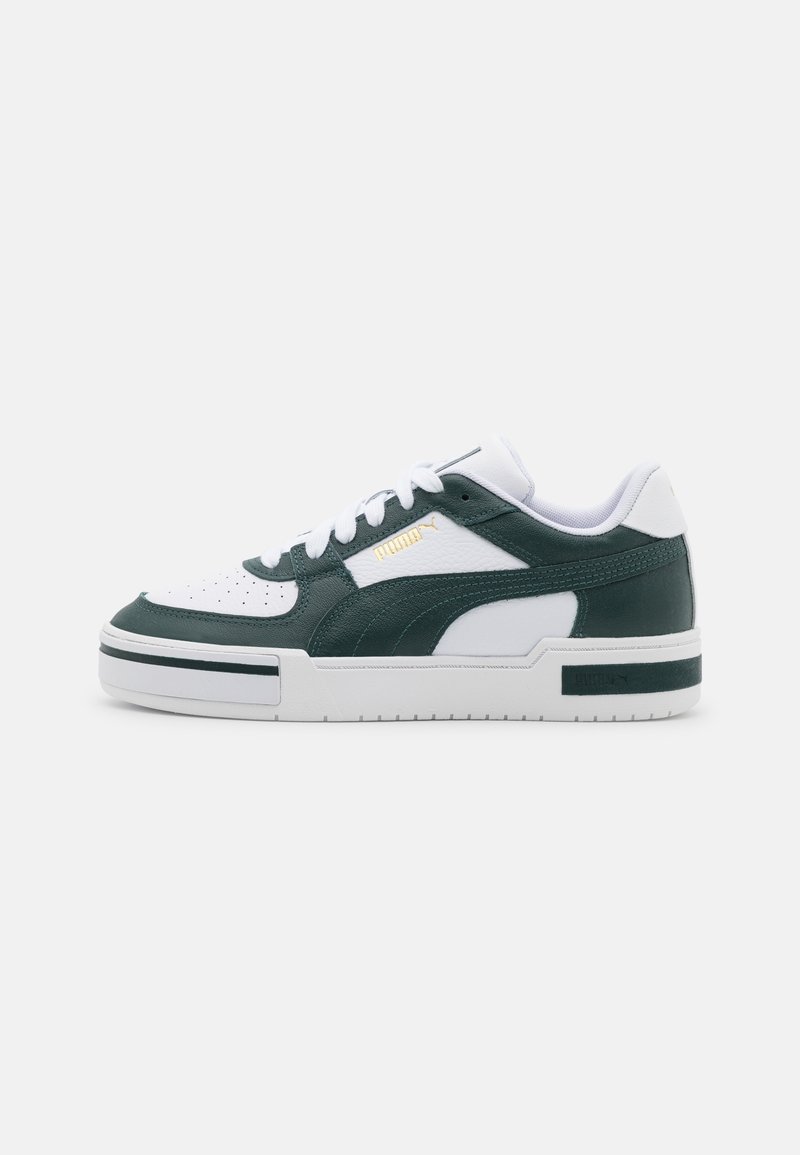 Baskets basses Puma en cuir blanc et vert foncé avec lacets blancs, bout perforé et semelle blanche épaisse sur fond uni.