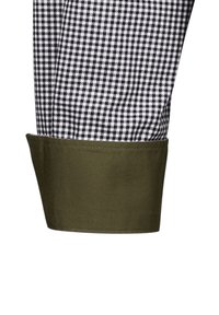 Tessuto a scacchi bianco e nero con dettagli verde al polsino, caratterizzato da una texture liscia e una finitura pulita all'orlo.