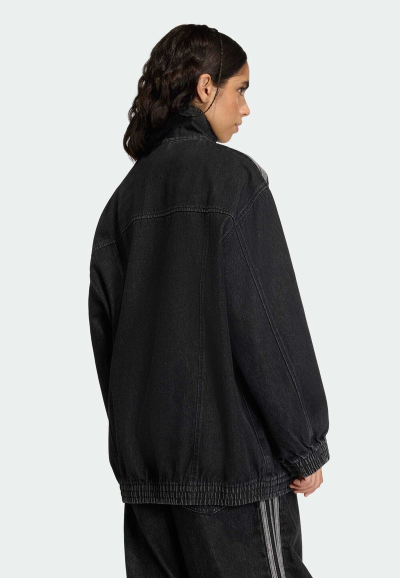 Black denim jacket with a relaxed fit, featuring an elasticated hem and high collar. Back view shows simple stitching and no visible hardware.