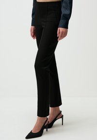 Zwarte op maat gemaakte pantalon met een strak ontwerp, voorzien van een slim fit en verticale naaddetails. Gekocht met zwarte puntige hakken.