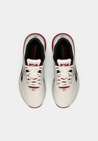 Hvite og røde Reebok Nano X-sko med et teksturert mesh-overside, svarte detaljer og hvite lisser. Merkbar logo på tungen.