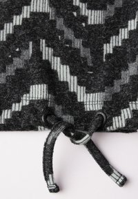 Grått mönstrat tyg med svarta och vita horisontella ränder, med dragsnöre och en slät textur nära nederkanten.