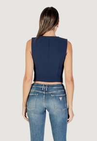 Crop top marine avec un design structuré aux épaules, associé à un jean ajusté bleu clair doté d'une petite patch logo sur la poche arrière.