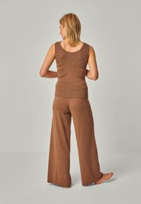 Braunes, geripptes, ärmelloses Top, kombiniert mit passenden, weit geschnittenen Hosen. Der Stoff ist strukturiert und hat eine weiche Oberfläche, mit einem entspannten Schnitt.