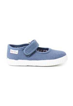 Zapato de lona azul con suela de goma blanca, presenta una cinta de velcro y un corte redondo en la punta. El interior tiene un patrón a cuadros.