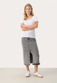 Witte top met korte mouwen en V-hals, met een textuurontwerp; grijze denim rok met een split aan de voorkant; gecombineerd met witte sneakers.