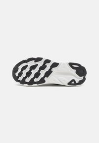 Suola di scarpa da corsa in bianco e nero con superficie in gomma testurizzata, scanalature flessibili e motivi di trazione distintivi per una buona aderenza.