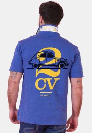 Homme portant un polo bleu à col relevé, avec un motif de voiture vintage et le texte « 2 CV » en jaune au dos.