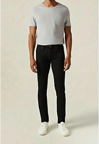 Šedé tričko s krátkým rukávem a kulatým výstřihem, kombinované s přiléhavými černými džínami a bílými teniskami. Hladká látka a minimalistický design.