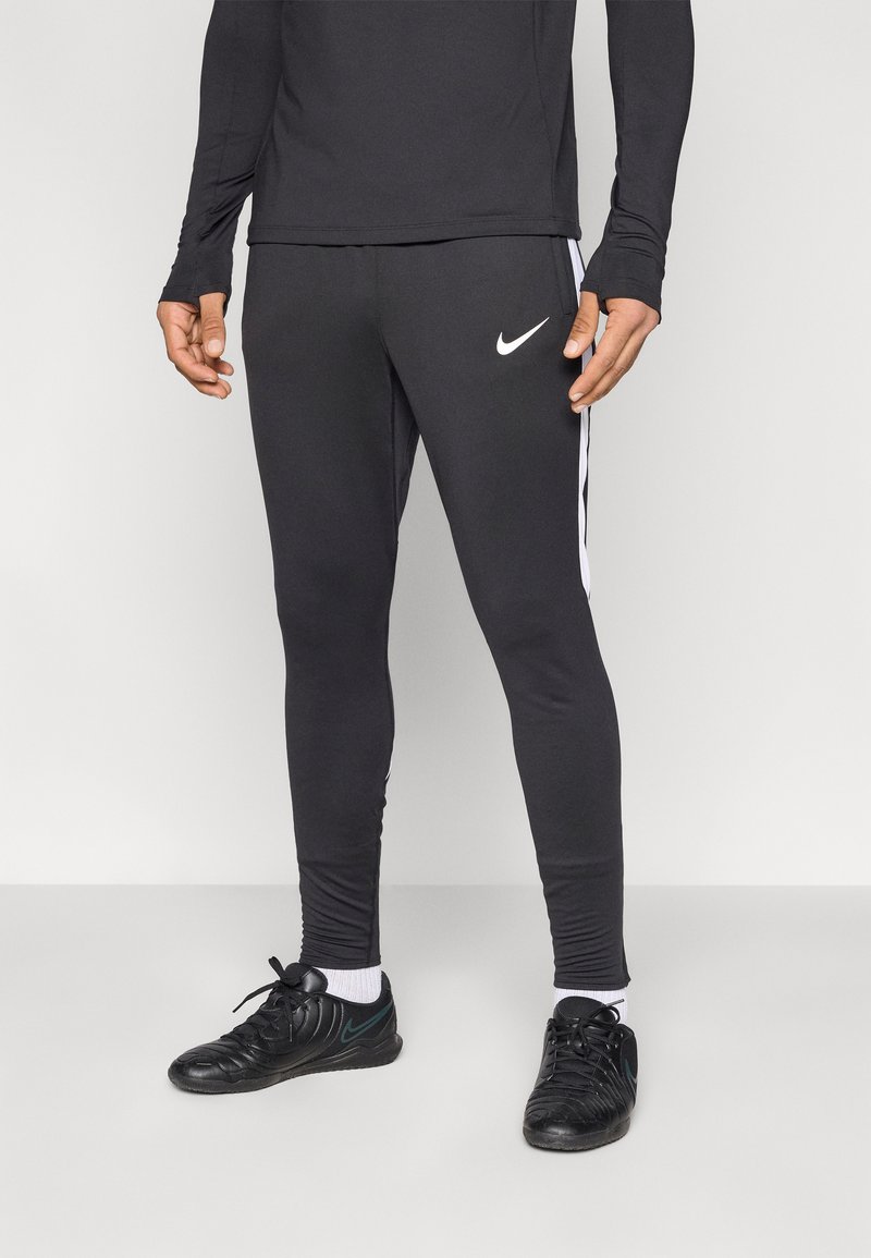 Μαύρο αθλητικό παντελόνι με λευκές πλευρικές ρίγες και λογότυπο Nike. Κατασκευασμένο από ελαστικό υλικό, με στενή εφαρμογή. Σετάρεται με μαύρα αθλητικά παπούτσια.