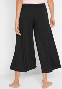 Pantaloni neri a gamba larga con una trama liscia, vita elastica e taglio alla caviglia. Caratterizzati da un design morbido e fluido per il massimo comfort.