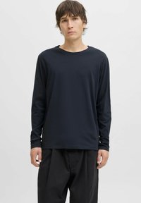 Marineblauwe longsleeve t-shirt van zachte stof, met een ronde halslijn en een relaxte pasvorm. Gepaard met losse zwarte broek.