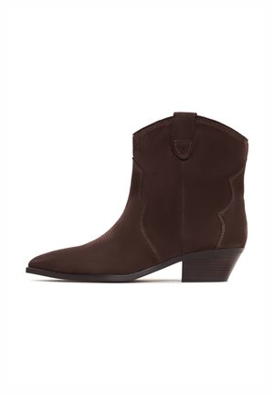 Brown suede cowboy boots with a pointed toe and low stacked heel, featuring decorative stitching and a pull tab at the top.