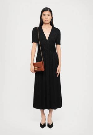 Black midi dress with short sleeves and V-neck, featuring a textured fabric and gathered waist. Paired with a brown crossbody bag.