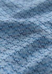 Helles blaues Gewebe mit einem detaillierten geometrischen Muster in Dunkelblau. Strukturiertes Gewebe, das komplizierte Designs und einen sanften Fall präsentiert.