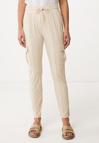 Beige joggerbyxor i mjukt material, med sidofickor, elastisk midja med dragsko och minimalistisk design.