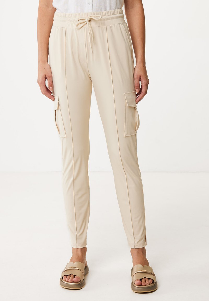 Beige joggerbyxor i mjukt material, med sidofickor, elastisk midja med dragsko och minimalistisk design.