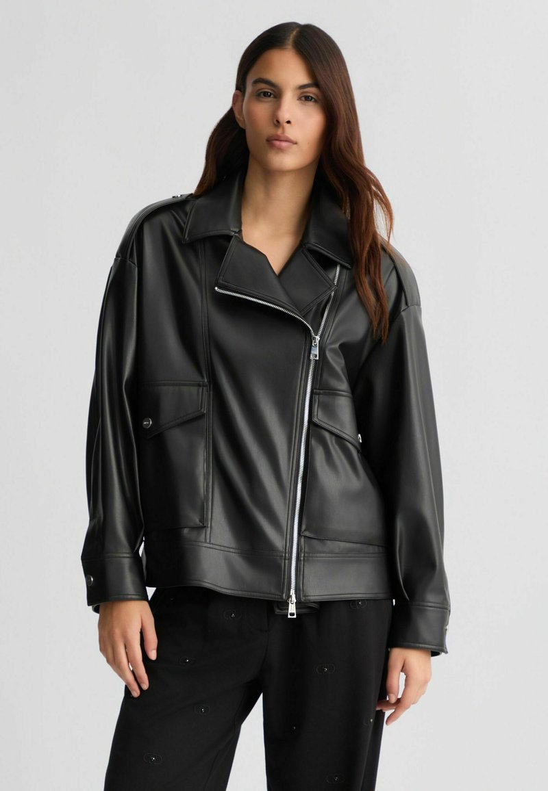 Giacca da biker in pelle sintetica nera con ampio colletto, zip asimmetrica e due tasche frontali; vestibilità ampia con una texture liscia.