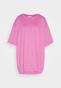 Camiseta rosa de gran tamaño hecha de algodón suave, con cuello redondo, mangas cortas y un corte relajado con aberturas laterales.