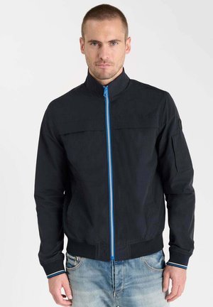 Dunkelblaue Bomberjacke mit hohem Kragen, Frontreißverschluss mit blauer Einfassung und gerippten Bündchen. Gestaltet mit einem klaren, minimalistischen Design.