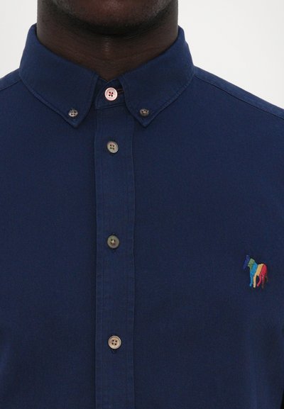Cămașă bleumarin cu nasturi, dotată cu guler, având nasturi maronii și un logo brodat cu un cal multicolor pe partea stângă a pieptului.