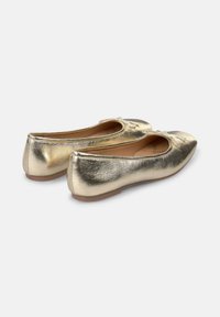 Bailarinas doradas con un acabado metálico, puntera redondeada y detalle de lazada decorativa. Suela ligeramente flexible con una textura suave.