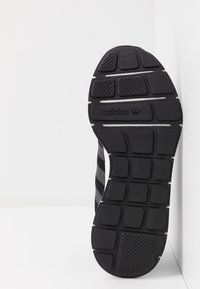 Svart sneakersula med texturerad gummi, distinkt mönster och vita accenter, med "Adidas"-logotyp prägla.