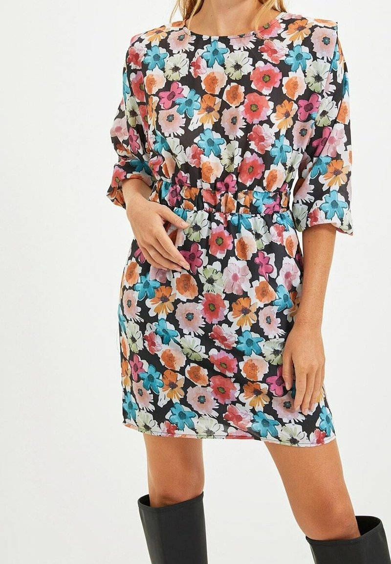 Robe florale avec un fond noir, des fleurs multicolores vibrantes, des manches courtes bouffantes et une taille élastiquée pour une coupe décontractée.