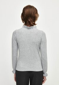 Pull gris à manches longues avec une finition texturée, doté d'un col et de poignets à volants, présenté de dos avec une coupe ajustée.