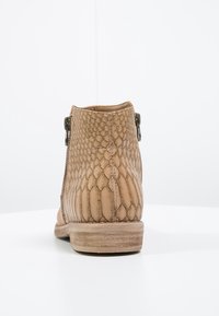 Tan ankle bootia valmistettu teksturoidusta käärmeennahasta, jossa on pinoattu korko ja sivuvetoketju. Pinta on sileä pohjassa.