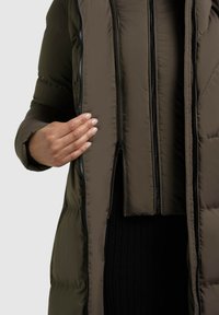 Olivengrøn puffjakke med lynlås foran, tætsiddende manchetter og quiltet tekstur. Inderlaget har ekstra lynlåse til justerbar dækning.