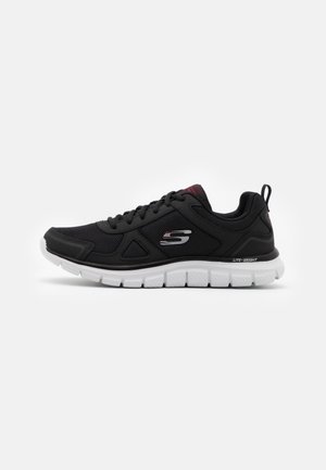 Chaussure de sport Skechers noire avec semelle blanche, empeigne en mesh, design à lacets, logo de la marque sur le côté et languette au talon.