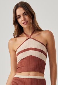 Top a colloque a coste in un caldo colore ruggine con strisce diagonali color crema. Presenta un design aderente e un neckline che mette in risalto.