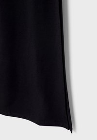 Vêtement en tissu noir avec une texture lisse, dotée de fentes sur les côtés et d'un design épuré et minimaliste. Convient à diverses occasions.