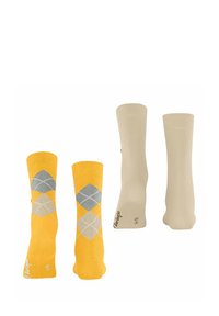 Gelbe Socken mit Rautenmuster in Grau- und Weißtönen, kombiniert mit einfarbigen beigen Socken. Schmeichelnde Textur, gestrickter Stoff.