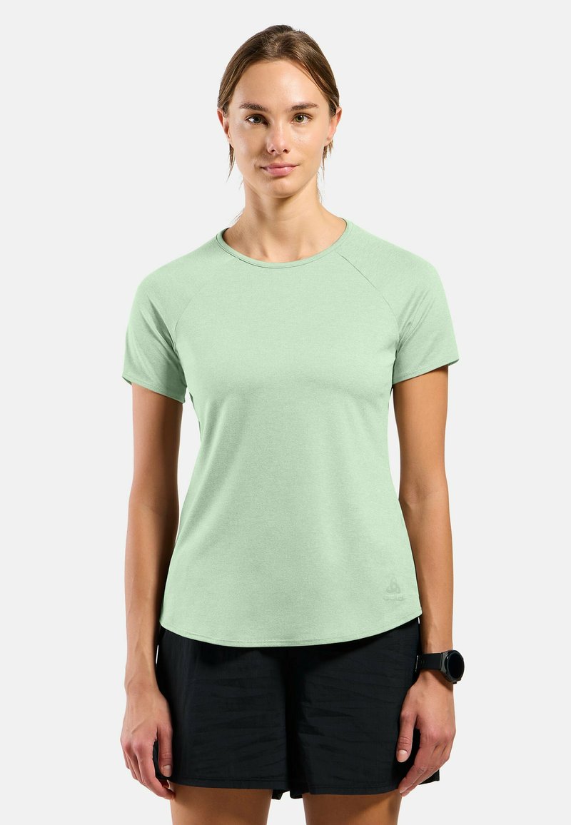 Light green short-sleeve athletic shirt with a round neck, smooth texture, and raglan sleeves, paired with black shorts.