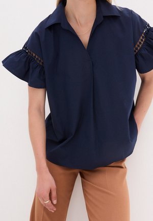 Blusa blu navy con scollatura a colletto, maniche corte a volant con dettagli in pizzo, e vestibilità ampia, realizzata in tessuto leggero.