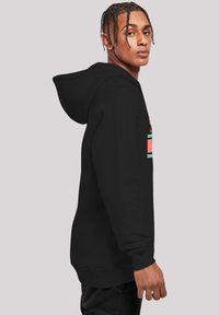 Felpa nera con cappuccio, dotata di tasca frontale, coulisse e un design grafico colorato sul petto, con polsini e orlo a costine.