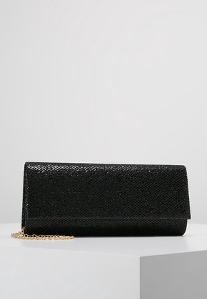 Pochette noire texturée avec rabat et chaîne dorée, présentée sur une surface blanche devant un fond gris.